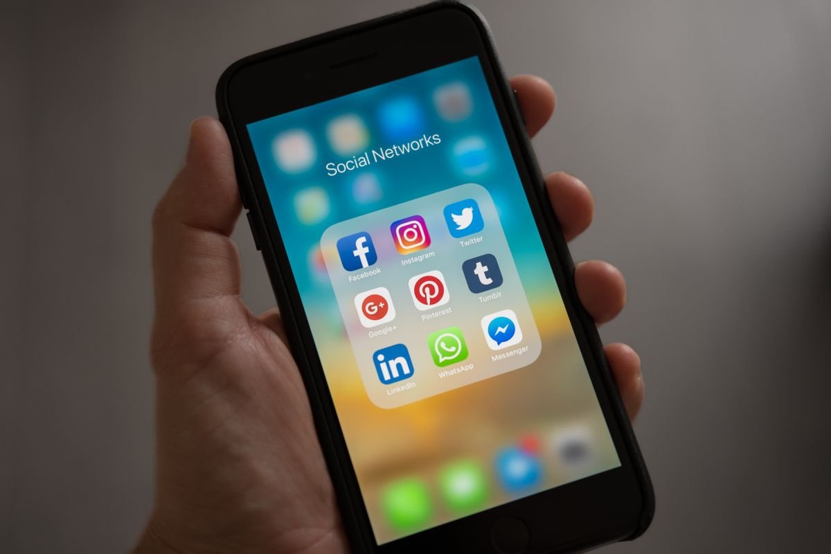 Hand holding a phone open to social media apps